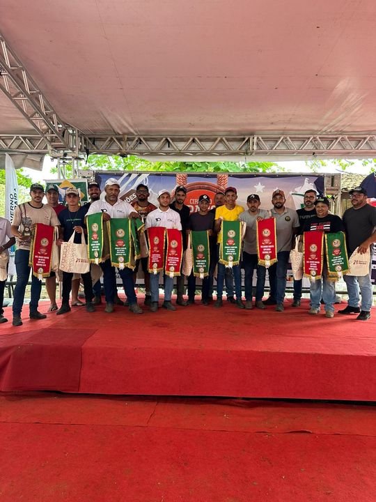 Tratadores da Fazenda Campinas no palco de uma exposição, segurando as faixas de premiação